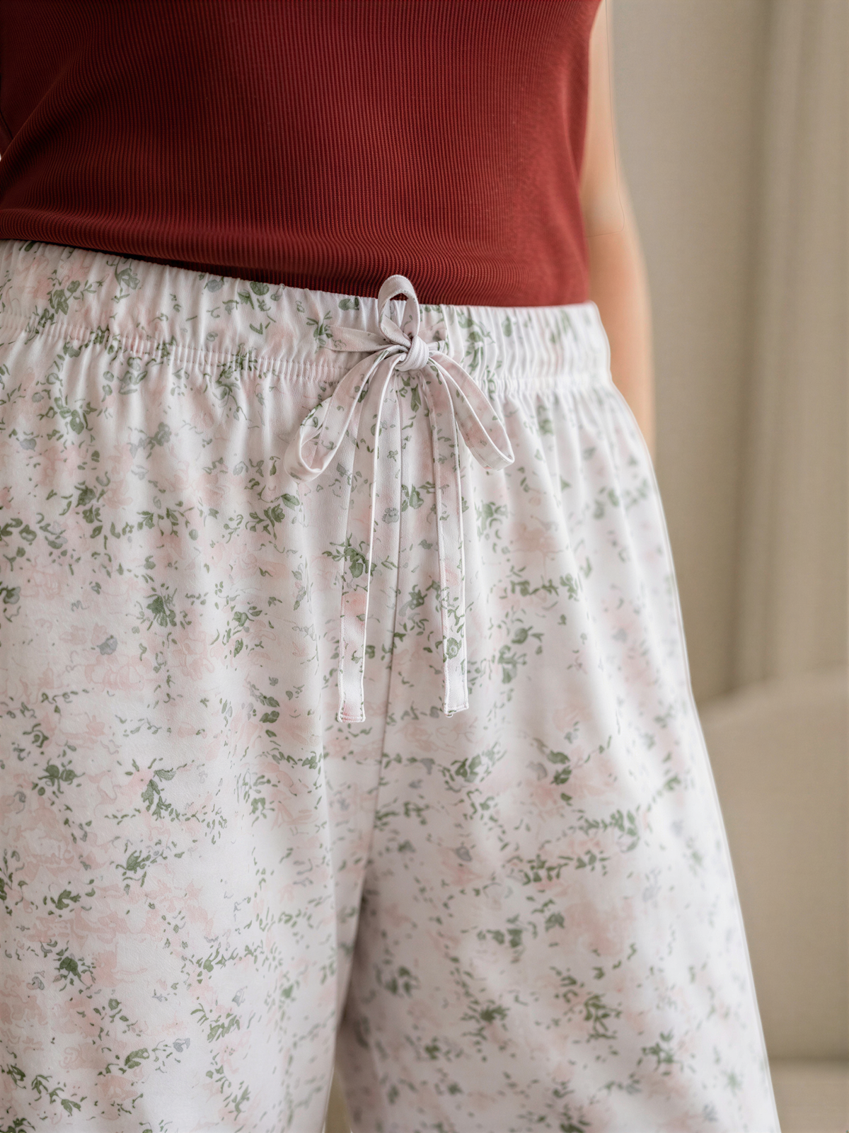 A close-up view of a person wearing a red top and floral print pants.