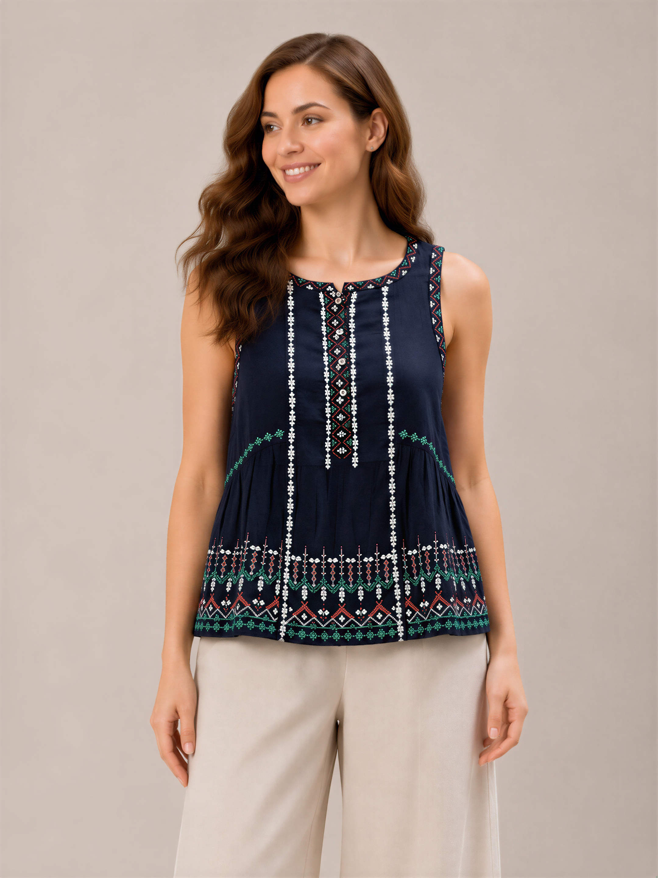 A woman with long brown hair is smiling and posing in a navy blue sleeveless top with a patterned design.