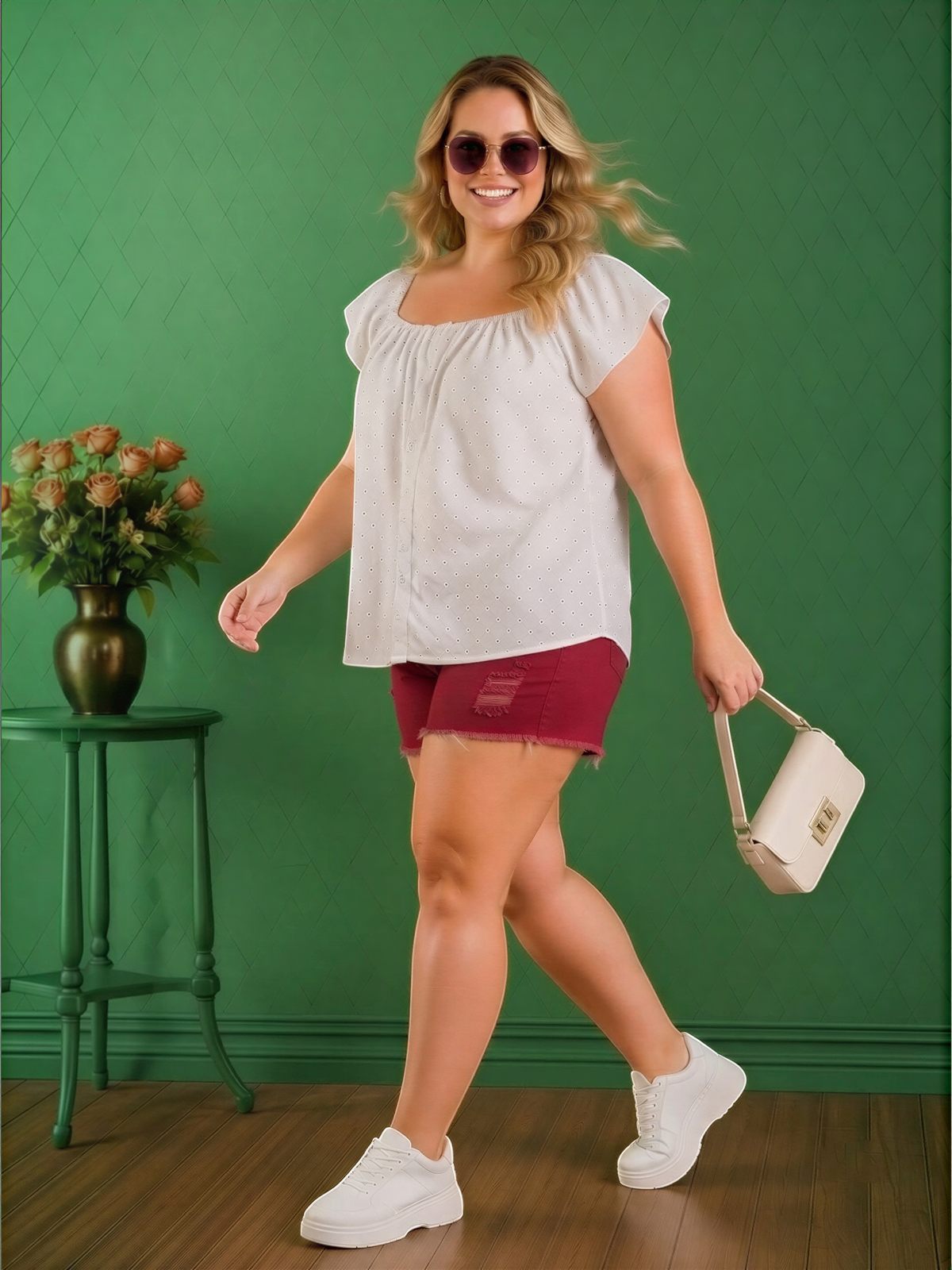 A woman in a white blouse and red shorts is walking in front of a green wall, holding a white purse.