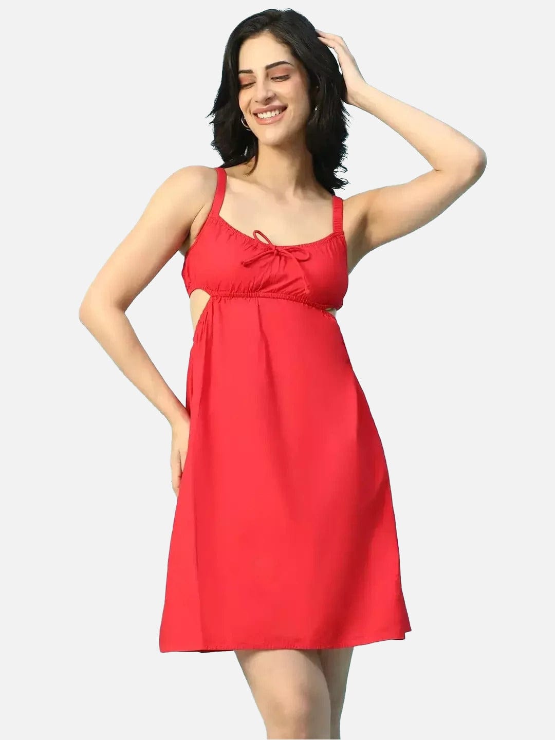 A woman wearing a red dress with a bow detail, smiling and posing with her hand on her head.