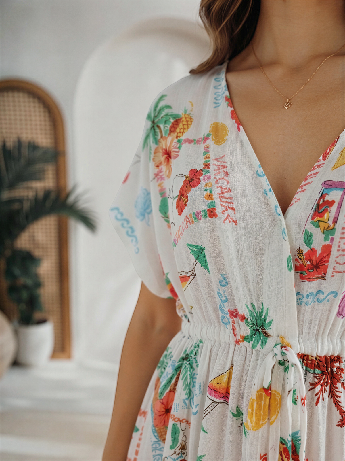 A woman wearing a colorful, printed dress with tropical designs, including palm trees, flowers, and hibiscus.