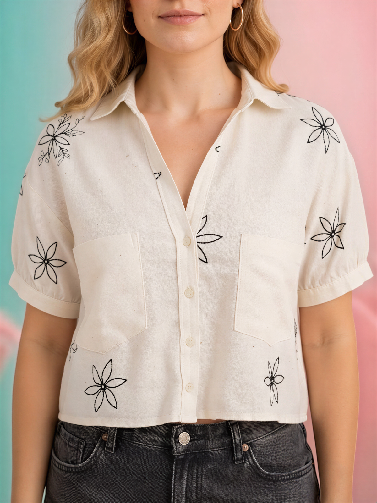 A woman wearing a white blouse with black flower designs on it, paired with black pants.